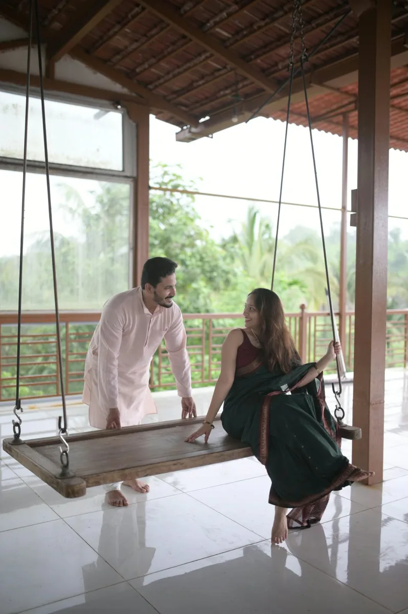 The couple smiling by a wooden swing