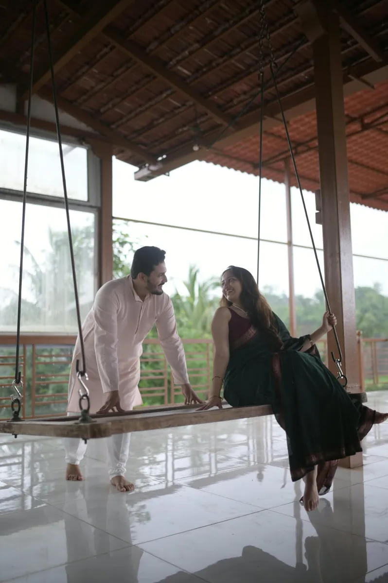 The couple laughing together on a wooden swing