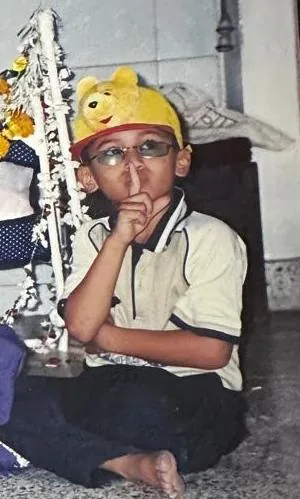 Saurabh as a little boy, in a yellow Pooh cap